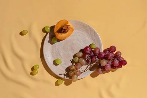 Cut fresh peach and grape on homemade ceramic plate on yellow tablecloth, Stock Photos