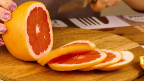 Cut An grapefruit Into a lot Slices on a plank Stock Footage 233620672