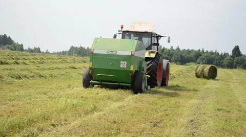 Cut grass compress equipment rides through the field work Stock Footage 34349873