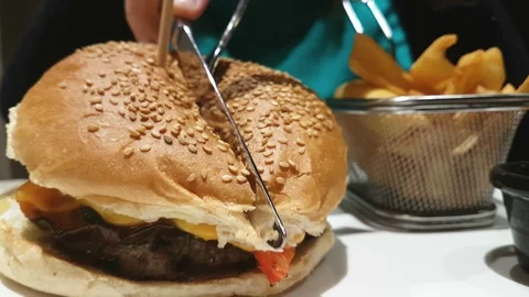 Cut in half angus burger on grain bun with tomato relish, lettuce and cheddar. Video stock 102214043