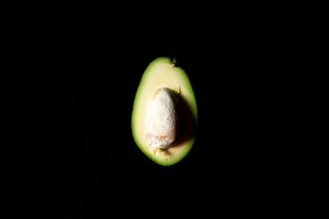 Cut in half avocado with bone, on a black background Stock Photos