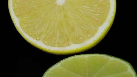Cut in half Fresh lemons and limes rotating in a circle, black background, and Stock Footage 146277805