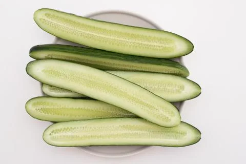 Cut in half lengthwise cucumbers on a plate on a white table Stock Photos