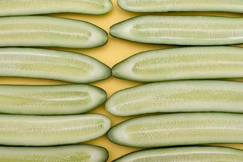 Cut in half lengthwise cucumbers spread along on a yellow background Stock Photos