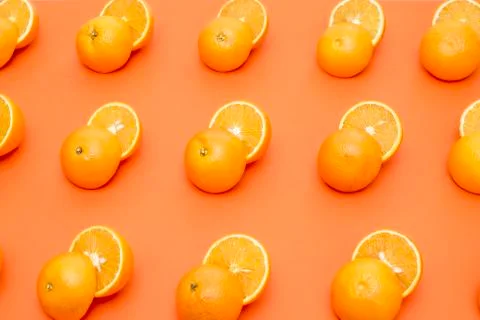 Cut in half oranges arranged in a row on an orange background Stock Photos