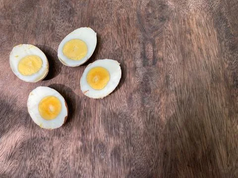 Cut in half of two hard-boiled eggs on natural brown wood table Photos
