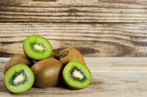Cut kiwi folded in a pile on a wood background Stock Photos