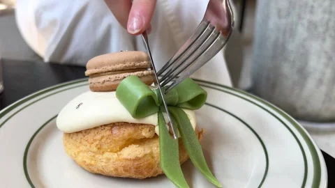 Cut with a knife and fork dessert beautiful delicious eclair with a green bow Stock Footage 277260987