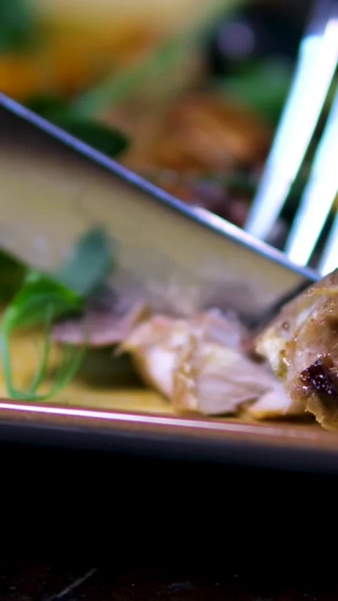 Cut with a knife and fork grilled mackerel fish on a black plate with lemon Stock Footage 323529380