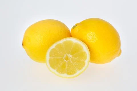 A cut lemon in front of two lemons Stock Photos