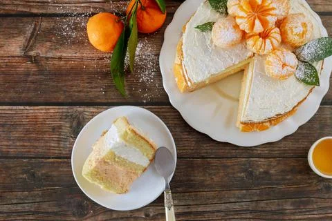 Cut mandarin sponge cake decorated with fresh tangerines. Stock Photos