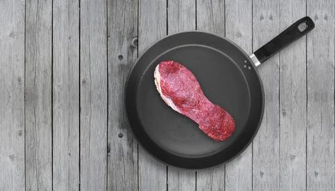 Cut of meat in the shape of shoe sole on pan. Tough meat. Stock Photos