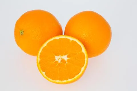 A cut orange in front of two oranges Stock Photos