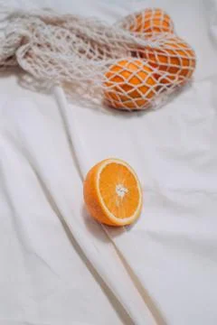 A cut orange on white blanket, sunlight Stock Photos