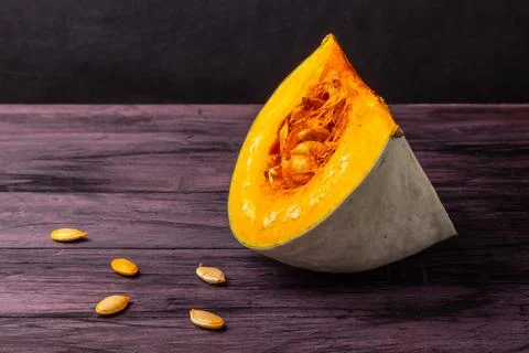 Cut-out pumpkin segment with seeds on a dark table Stock Photos