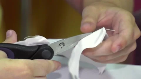 Cut a piece of white cloth with scissors. Stock Footage 106774071