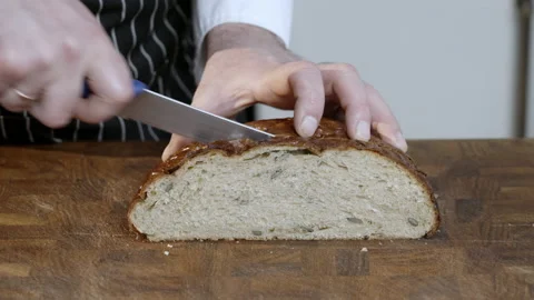 Cut into pieces loaf of dark bread, man cuts bread in the kitchen. Stock Footage 233618874