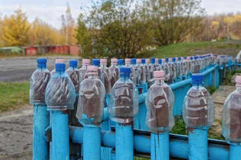 Cut plastic bottles are put on a blue fence Stock Photos