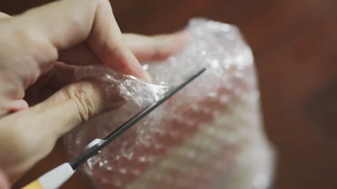 Cut a plastic bubble wrap packaging with scissors Video stock 291636975