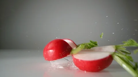 Cut radishes falling on water surface. Slow Motion. Video stock 128771446