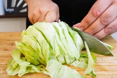 Cut raw cabbage on a cutting board with knife. Cook cuts cabbage Stock Photos