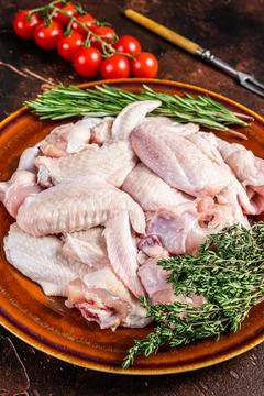 Cut Raw chicken wings in a rustic plate with thyme and rosemary. Dark background Stock Photos