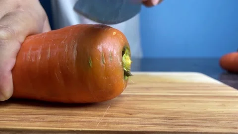 Cut raw organic carrot slice on a wooden chopping board at kitchen close up Stock Footage 234201151