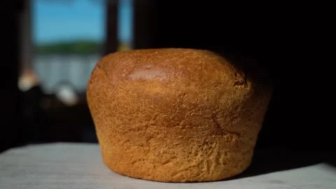Cut a slice of bread. Fresh bread on a table near the window close-up, lit by Stock Footage 134701420
