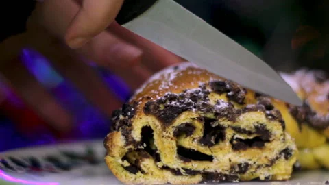 Cut a slice of Christmas chocolate cake with christmas lights on the background Video stock 99735609