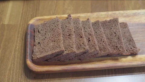 Cut slices of black bread lie on wooden rectangular plate. Stock Footage 255426314
