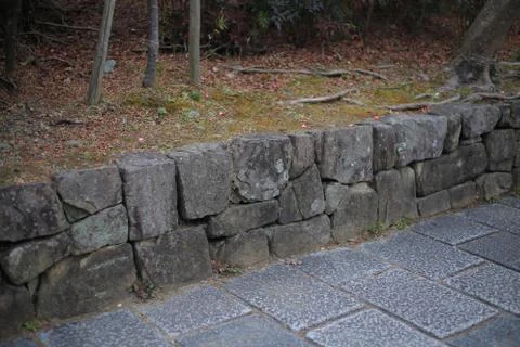 Cut stone retaining wall separate green area and rough granite stone slabs fo Stock Photos