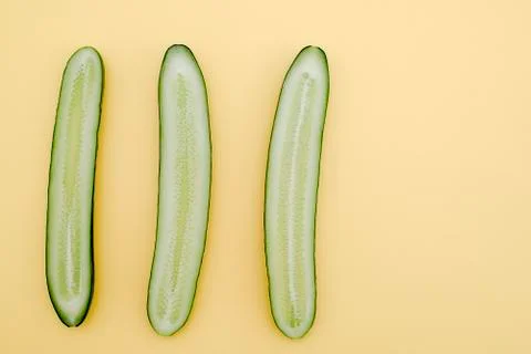 Cut three cucumbers in half lengthwise on a yellow background Stock Photos