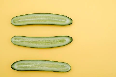 Cut three cucumbers in half lengthwise on a yellow background Stock Photos