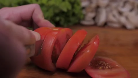 Cut tomato with knife on kitchen table slow motion Stock Footage 148340471