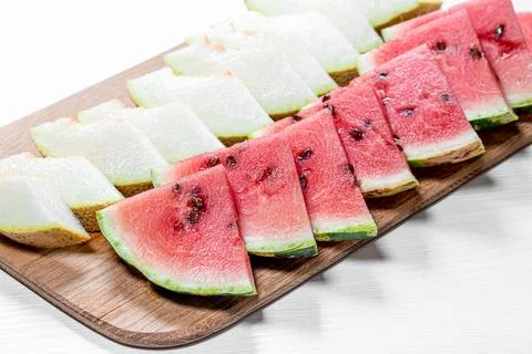 Cut triangular pieces of ripe watermelon and melon on kitchen Board Stock Photos