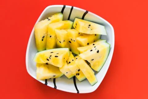 Cut off triangular slices of ripe yellow watermelon in white plate 库存照片