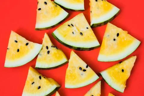 Cut off triangular slices of ripe yellow watermelon on white background Stock Photos