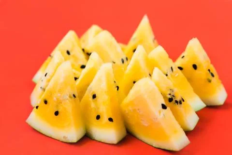 Cut off triangular slices of ripe yellow watermelon on white background Stock Photos