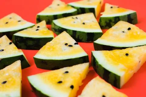 Cut off triangular slices of ripe yellow watermelon on white background Stock Photos