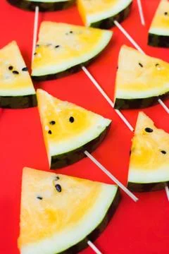 Cut off triangular slices of ripe yellow watermelon on white background Stock Photos