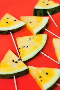 Cut off triangular slices of ripe yellow watermelon on white background Stock Photos