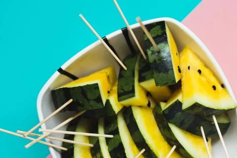Cut off triangular slices of ripe yellow watermelon on blue-pink background 스톡 사진