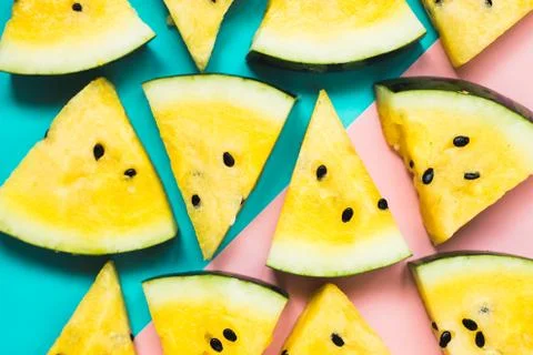 Cut off triangular slices of ripe yellow watermelon on blue-pink background 写真素材