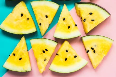 Cut off triangular slices of ripe yellow watermelon on blue-pink background 写真素材