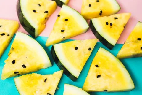 Cut off triangular slices of ripe yellow watermelon on blue-pink background 写真素材