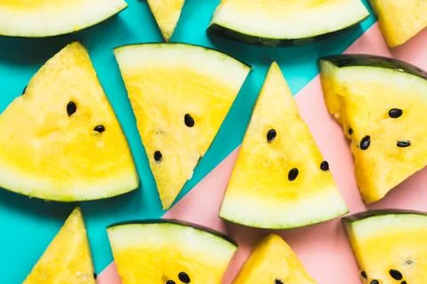 Cut off triangular slices of ripe yellow watermelon on blue-pink background Foto stock