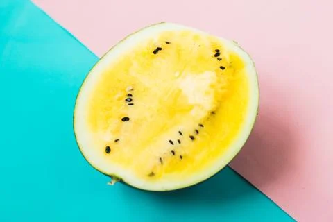 Cut off triangular slices of ripe yellow watermelon on blue-pink background 스톡 사진