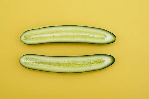 Cut two cucumbers in half lengthwise on a yellow background Stock Photos
