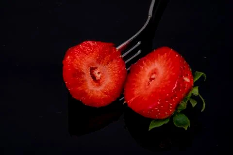Cut in two halves with a fork on black background dark Stock Photos