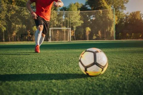 Cut view of man running to ball. He is going to kick it. Sun is shining outside Foto stock